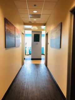 The image depicts a hallway with walls painted in shades of blue and yellow, leading towards an open door at the end.