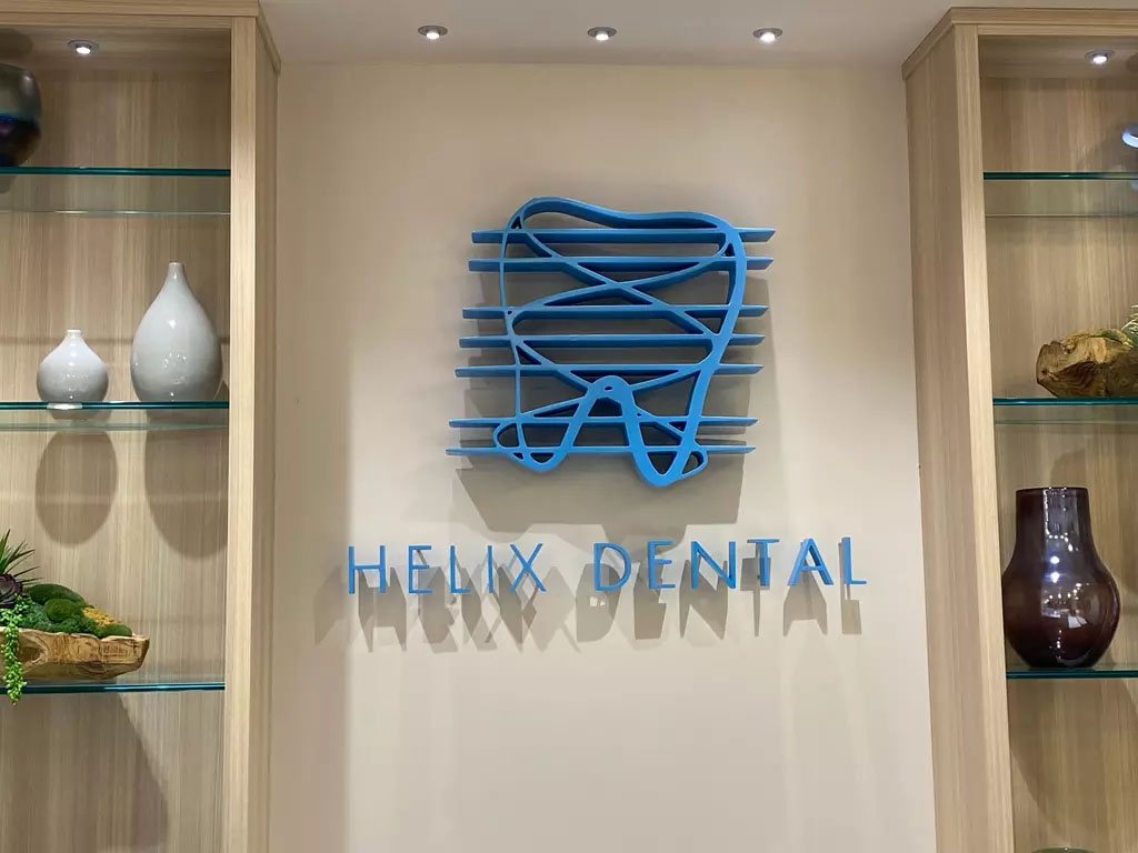 The image features a sign for  Helix Dental  with a modern design, displayed on a wall within an office setting.