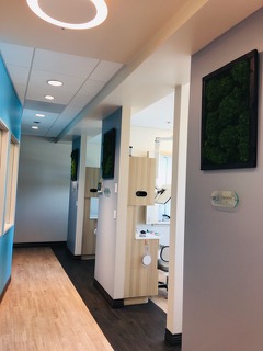 The image shows an interior view of a dental office waiting area with modern decor, including wall art and a clean, professional atmosphere.