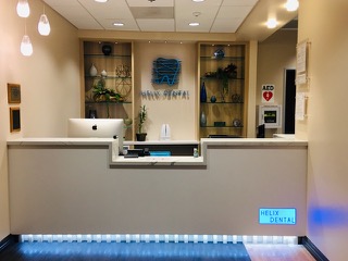 The image shows an interior view of a dental office reception area, featuring a modern design with a clean countertop, a sign with the name  Ave Dental,  a blue light on the floor, and a welcoming atmosphere.