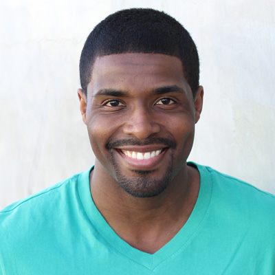 A man and woman posing closely together with smiles, set against a backdrop of a mountainous landscape.