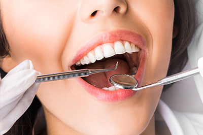 A woman undergoing dental treatment with a focus on her open mouth and the dentist s tools.