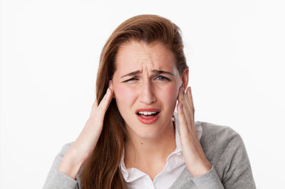 A woman with her hand on her head, appearing to be in pain or distress.