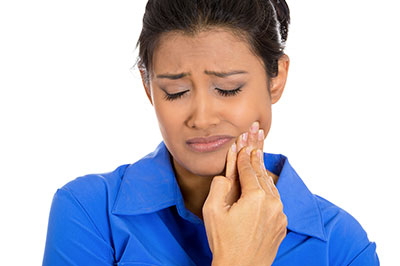 The image shows a woman with her mouth open, looking upwards with a concerned expression while holding her nose with her hand.