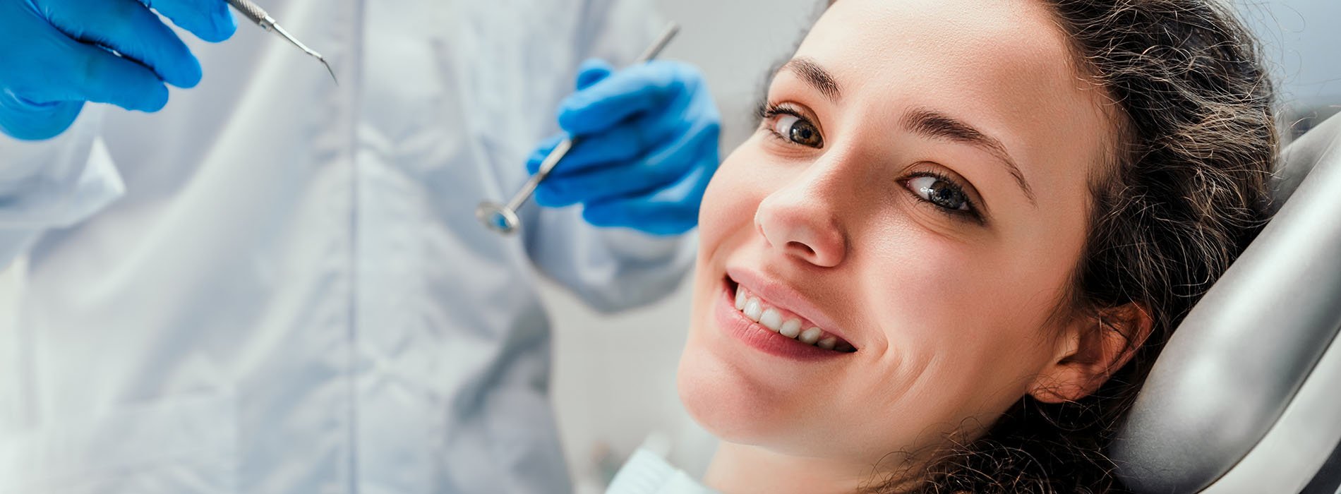 A woman receiving dental care with a dentist performing a procedure on her teeth.