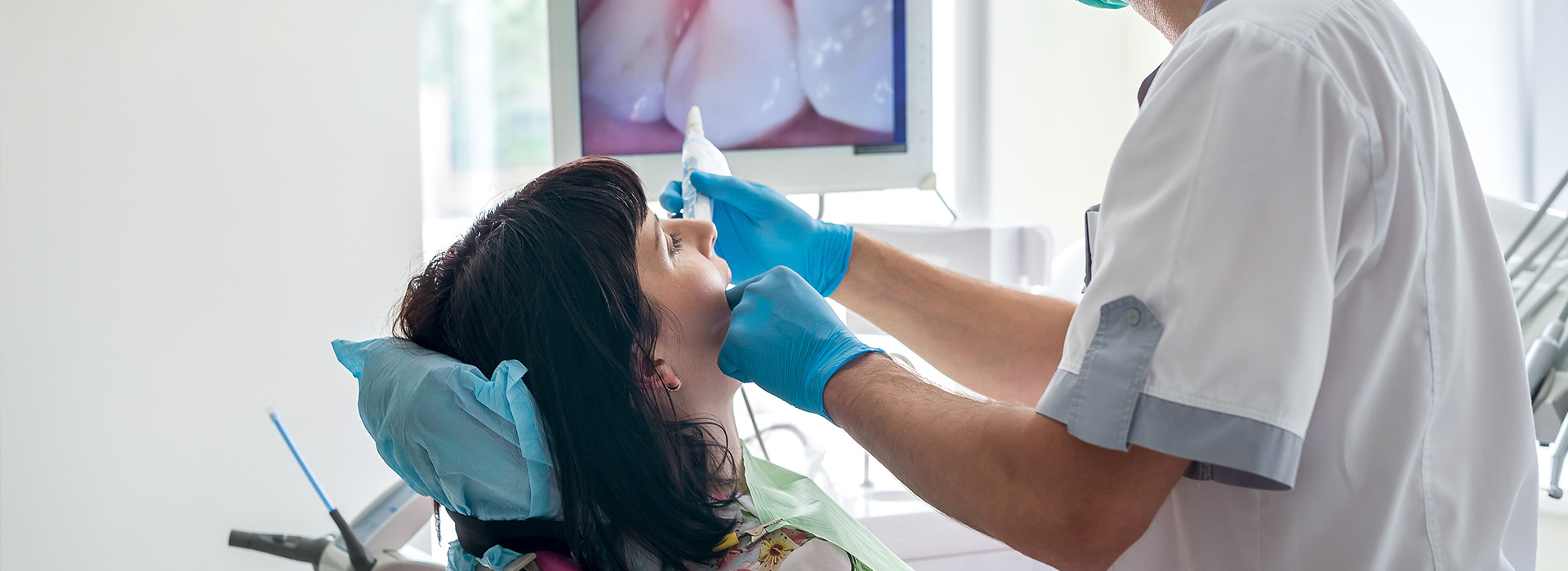 A dental hygienist performing an examination on a patient s mouth with the assistance of a dentist, using specialized equipment and tools.