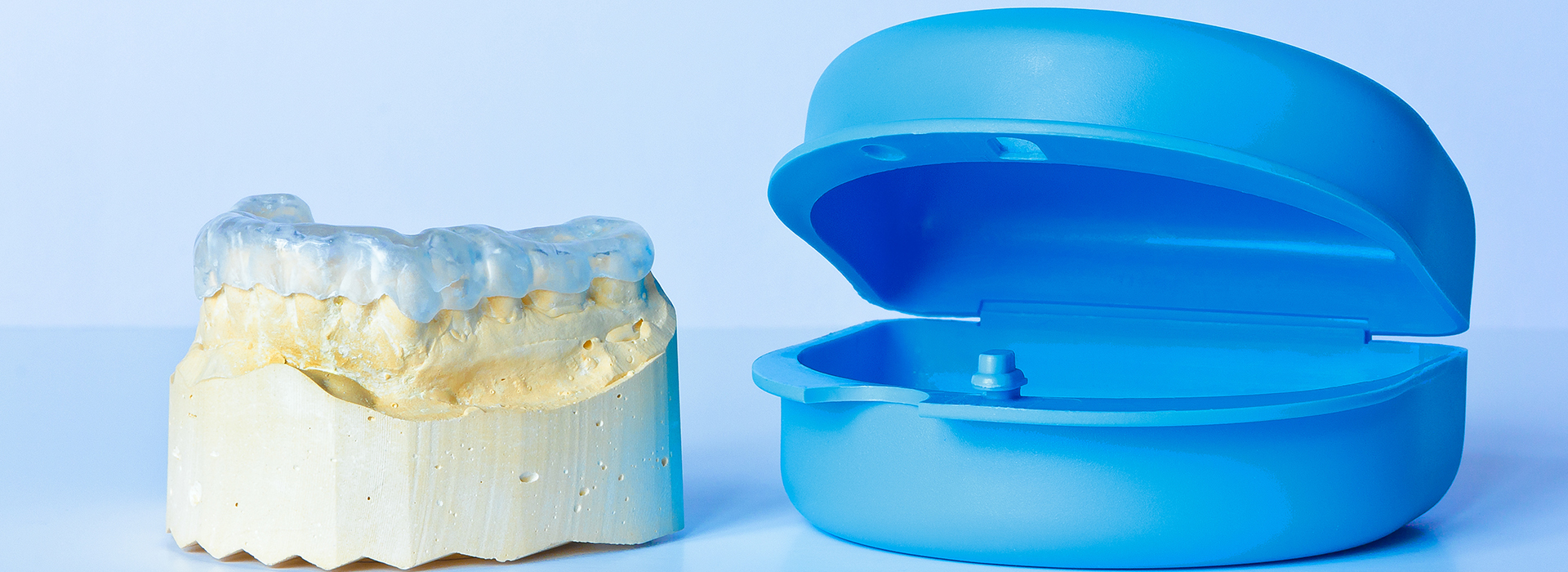 The image shows two dental models with a focus on the lower model, which has a blue acrylic base and a yellow acrylic upper model, placed next to each other against a white background.