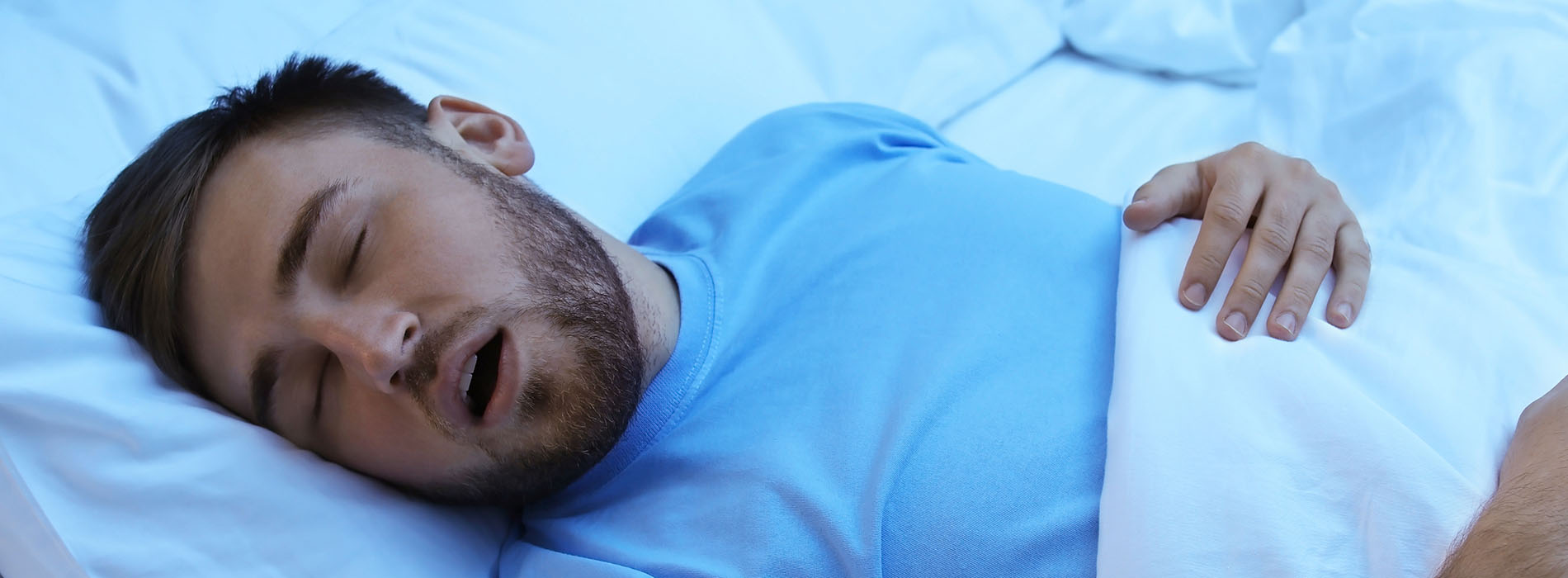 A man sleeping in bed with his mouth open, captured in a candid moment.