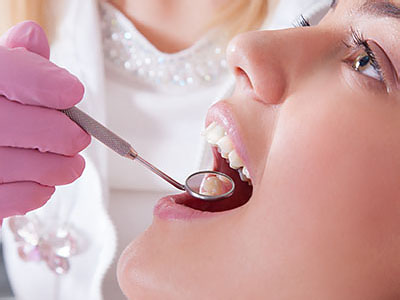 A woman receiving dental treatment with a dentist using a drill on her tooth.