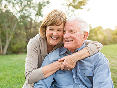 The image shows a man and woman embracing each other outdoors during daylight.