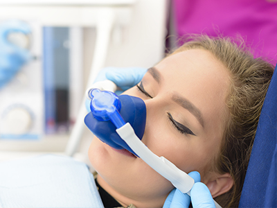 A person receiving medical treatment with an oxygen mask, attended by a healthcare professional wearing gloves.